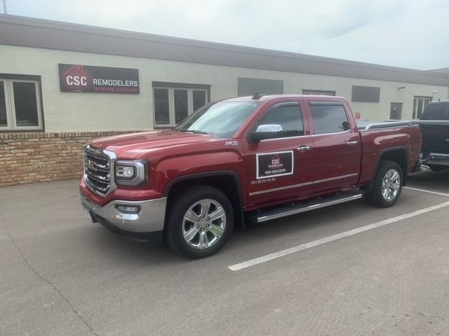 A red truck is parked in a parking lot in front of a building.
