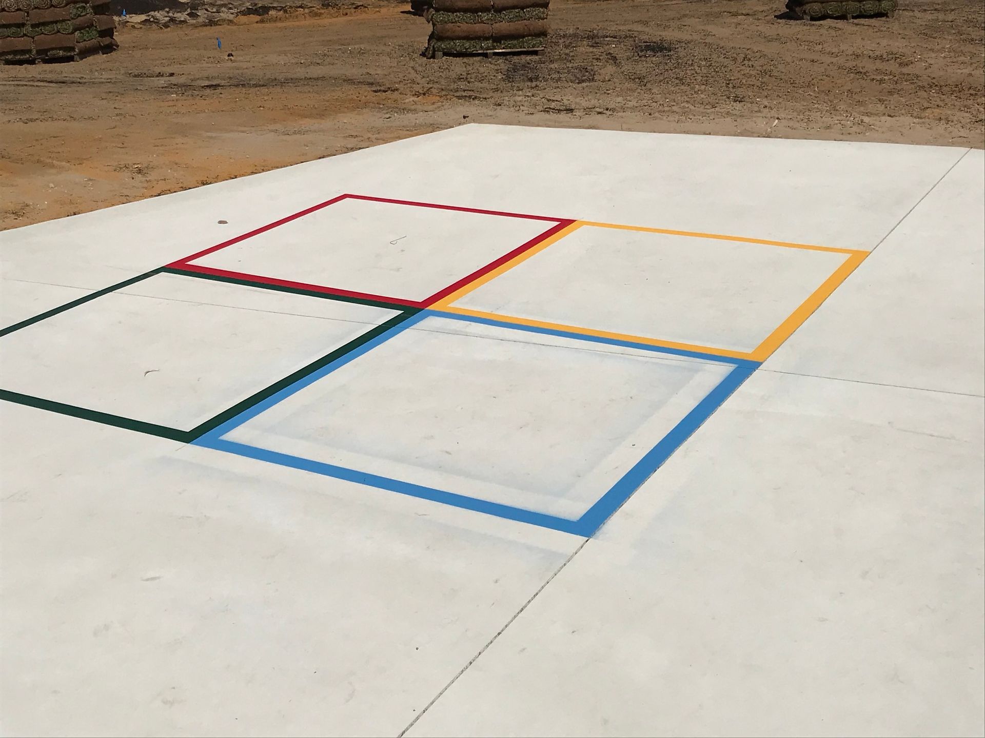 Concrete square with four colorful boxes painted on it, red, yellow, green, and blue.