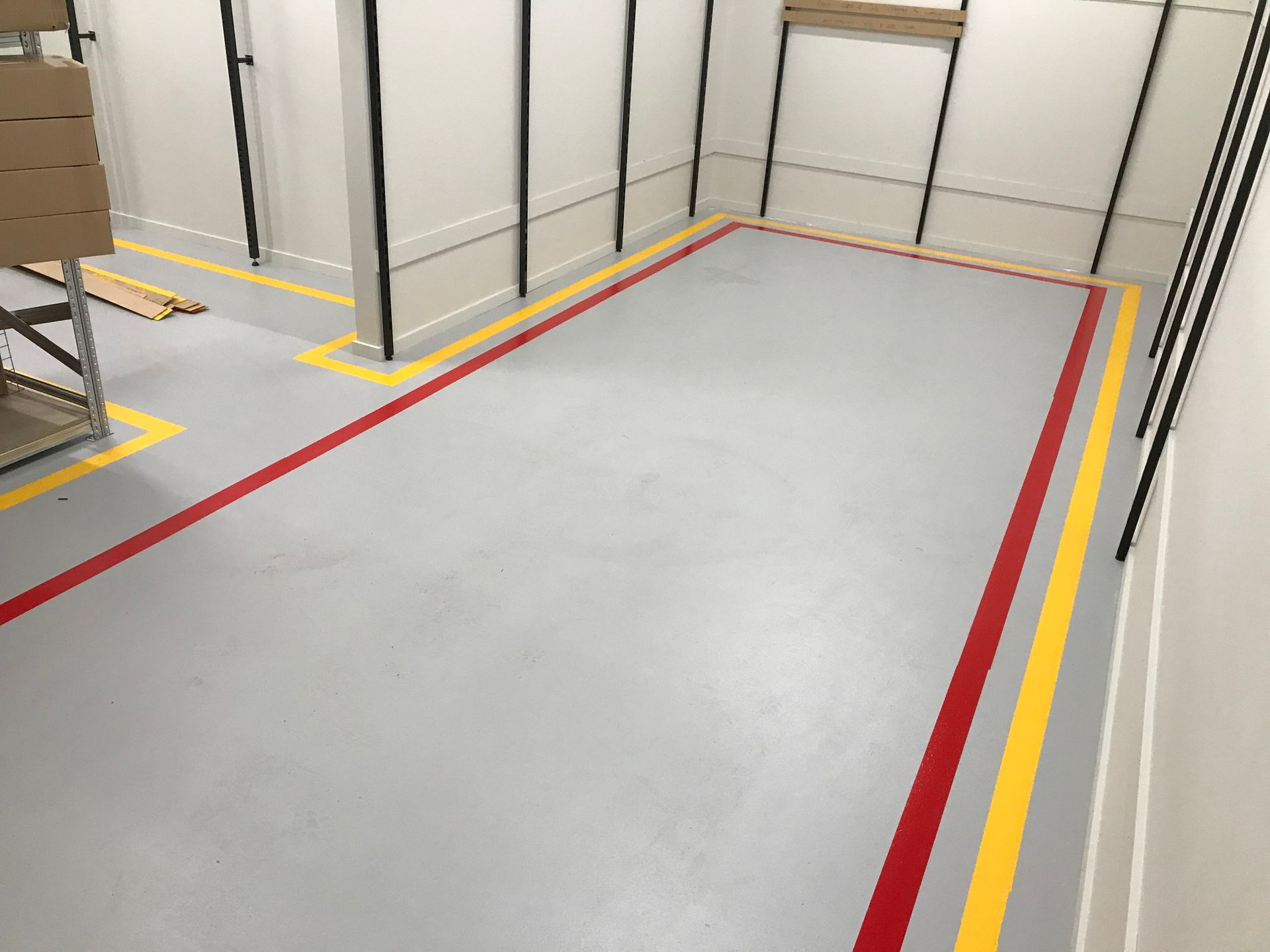 A warehouse floor with red and yellow painted lines, defining work zones.
