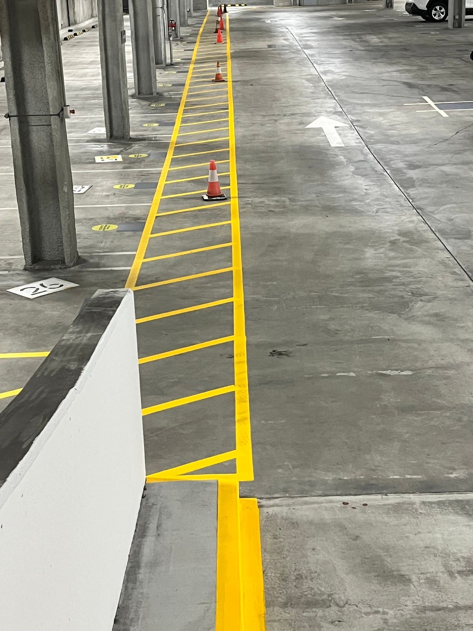 Parking garage lane marked with yellow lines and cones, arrow directing traffic.