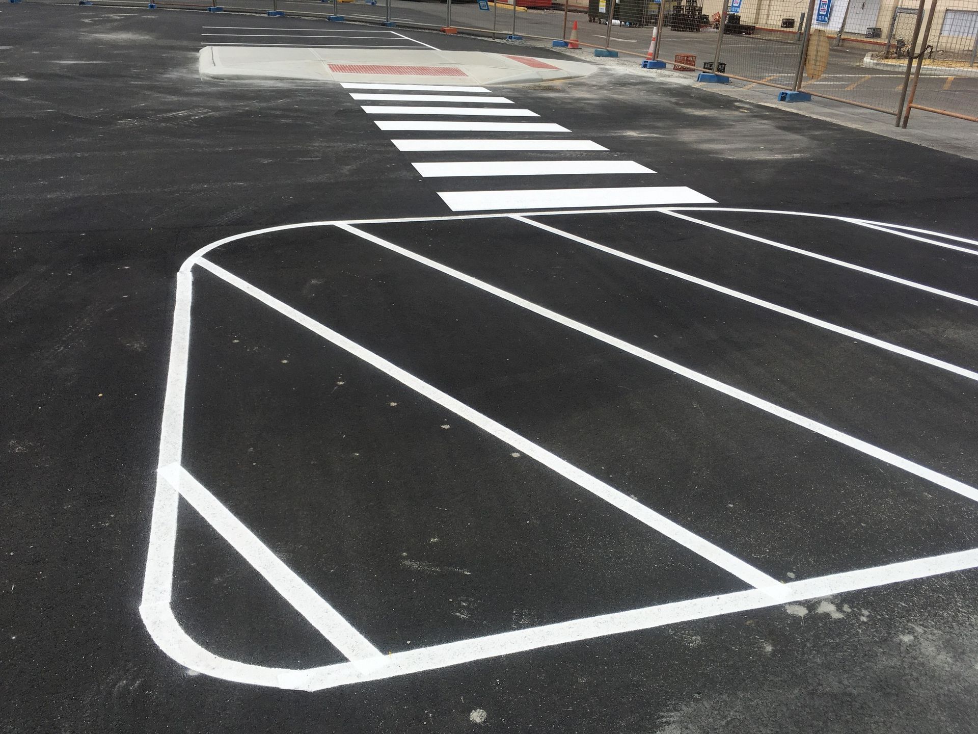 Black asphalt surface with white crosswalk and parking space lines.
