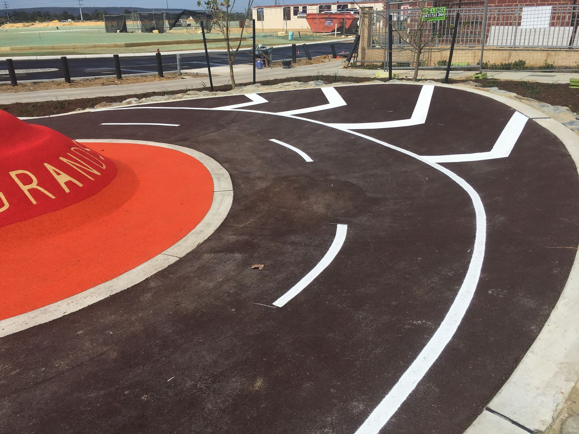 Playground with asphalt paths, white lines, and an orange structure.