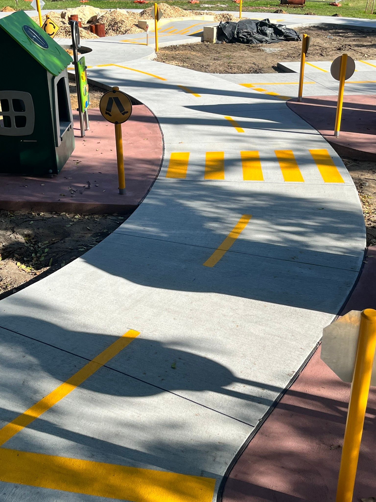 Playground with a road, crosswalk, and traffic signs.