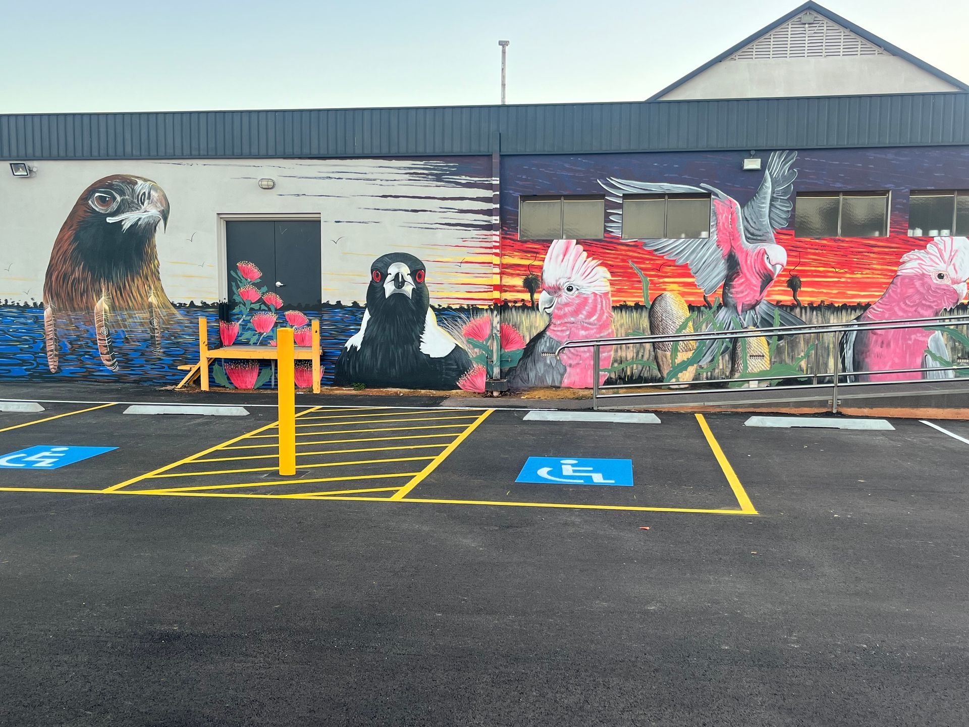 Mural of birds on a building exterior with accessible parking spaces in front.