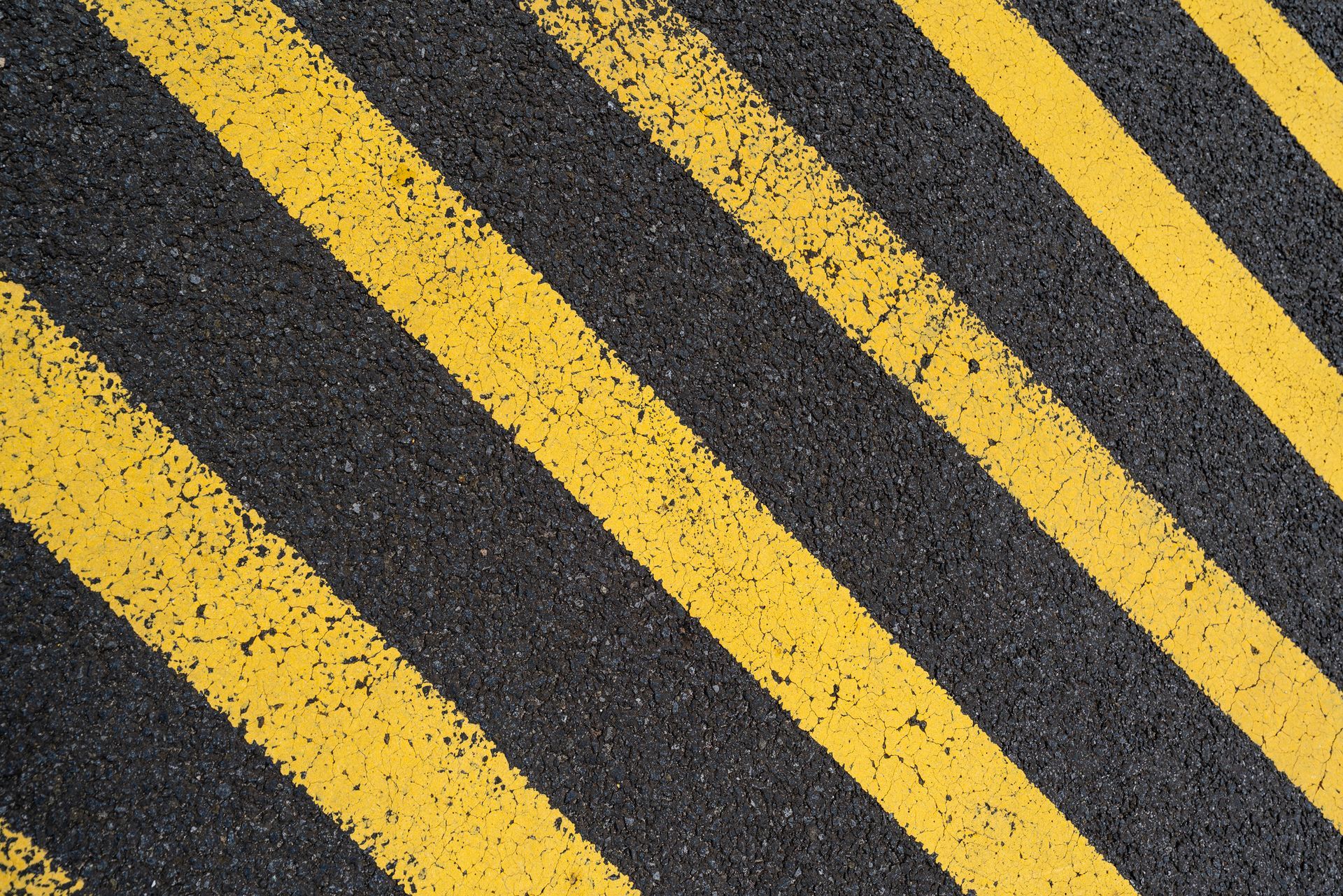 Diagonal yellow lines on asphalt road surface.