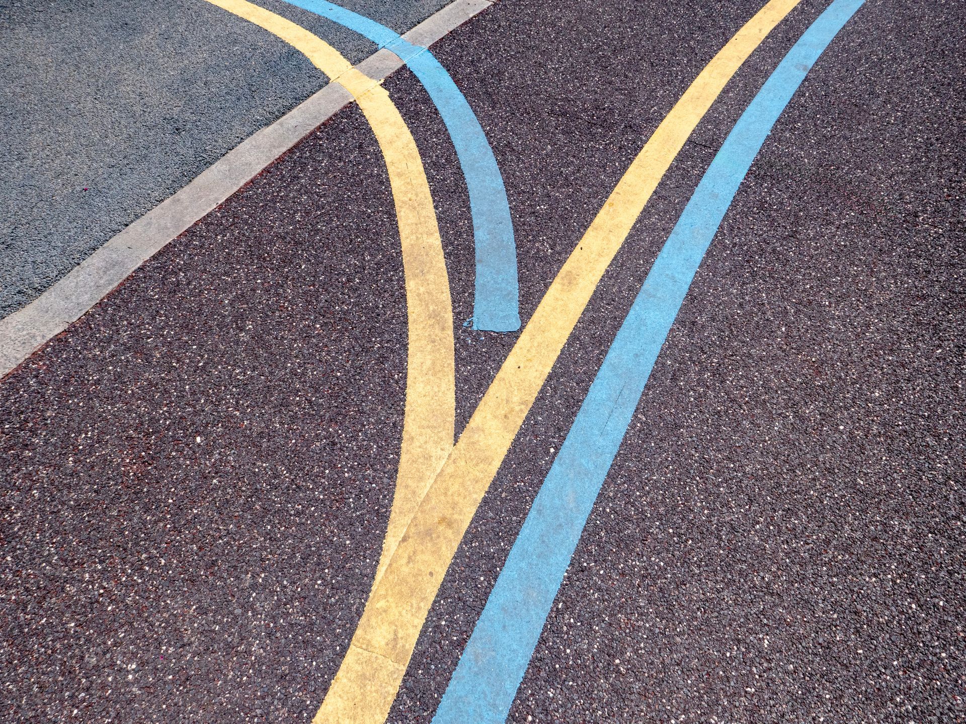 Yellow and blue lines diverging on asphalt road.
