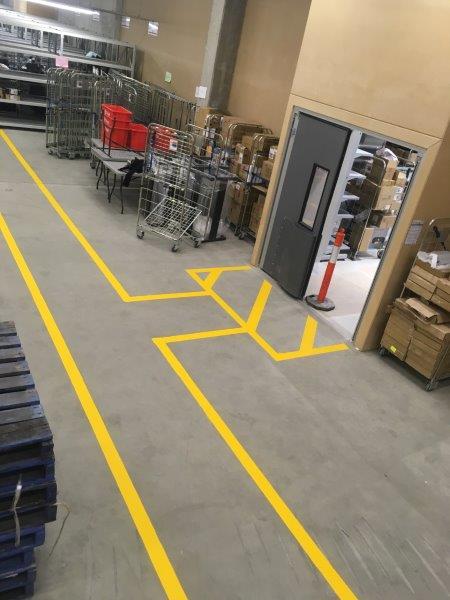 Warehouse floor with yellow painted lines for traffic flow and designated zones.