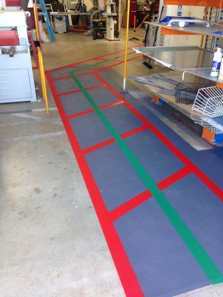 Floor painted with red and green lines in a workshop, marking pathways and work zones.
