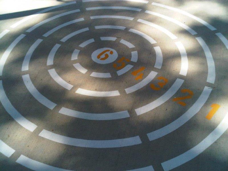 White concentric circles with orange numbers 1-6 painted on a concrete surface.