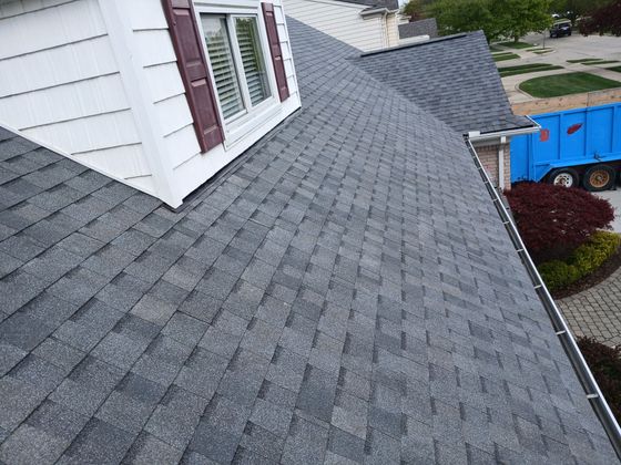 A roof of a house with a garbage truck in the background.