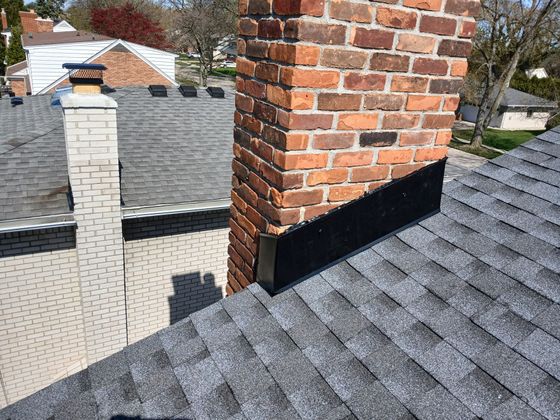 A brick chimney is on the roof of a house.