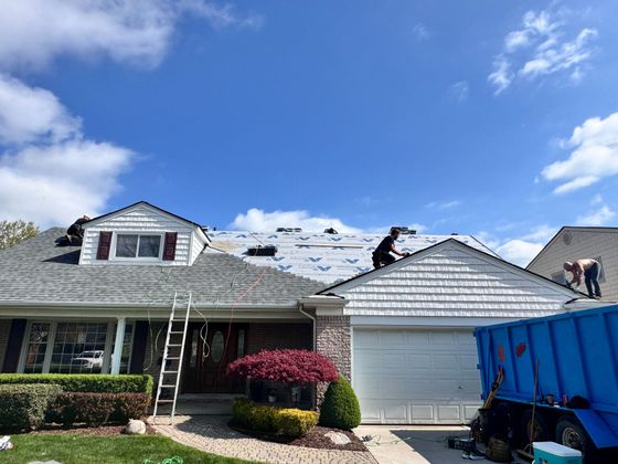 Two men are working on the roof of a house.