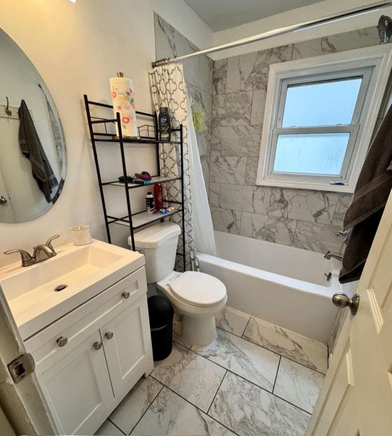 A bathroom with a toilet , sink , tub and mirror