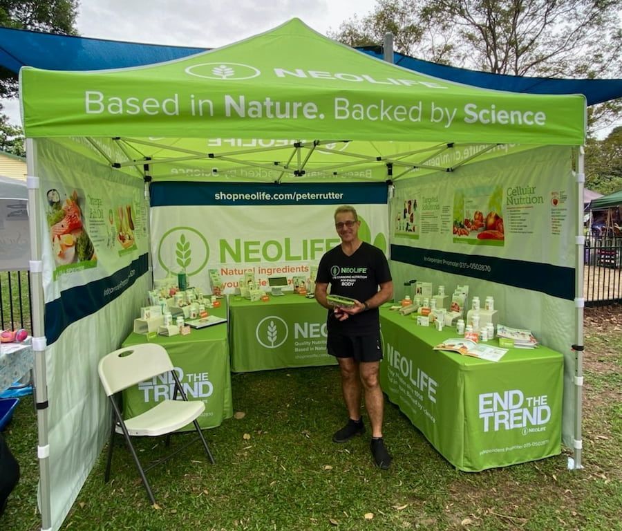 A Man Is Standing In Front Of A Neolife Tent — Vibrant Health - Vibrant Life In Yorkeys Knob, QLD