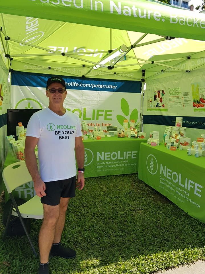 A Man Is Standing In Front Of A Neolife Tent — Vibrant Health - Vibrant Life In Yorkeys Knob, QLD