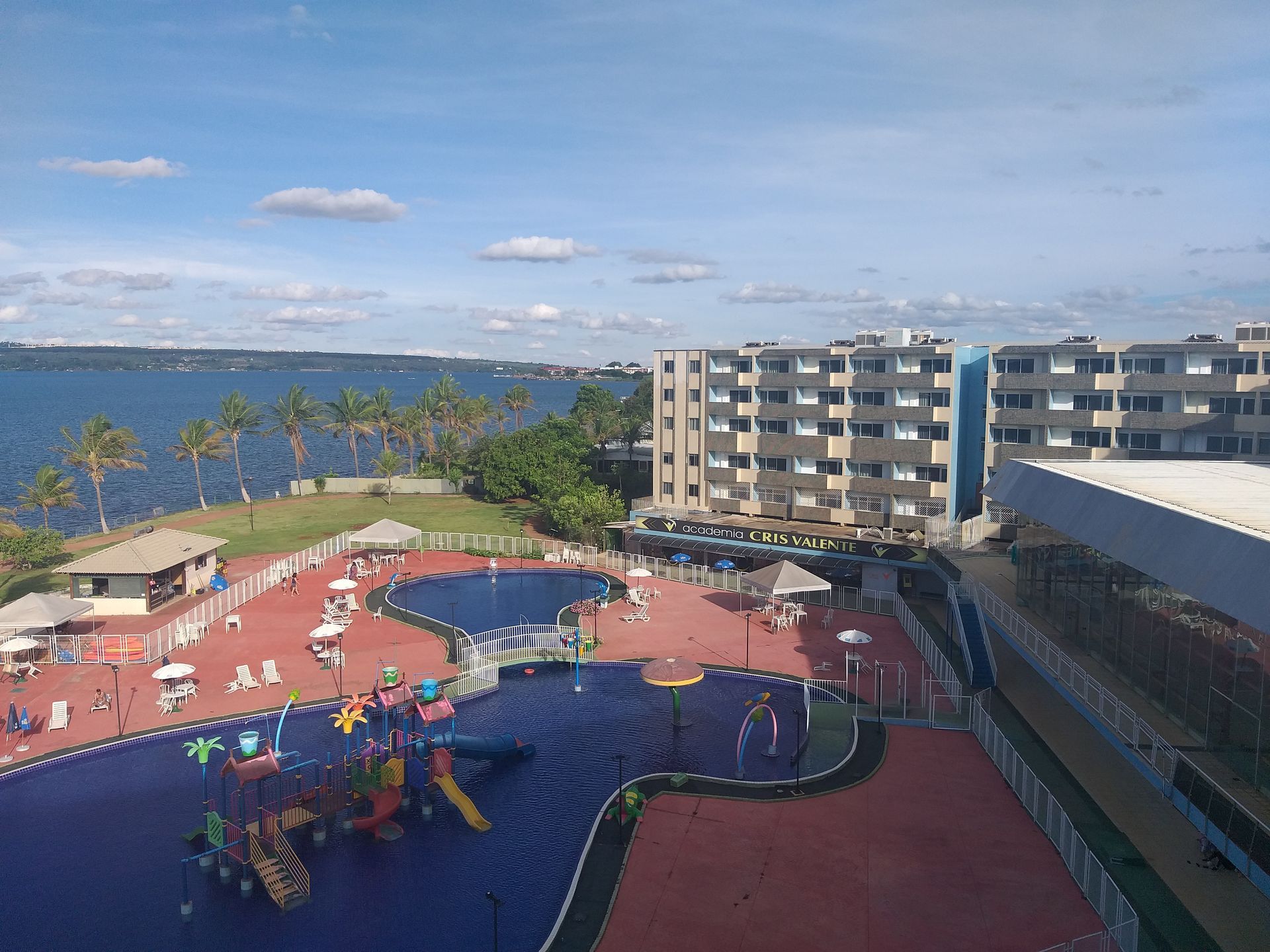 Uma vista aérea de uma grande piscina cercada por edifícios e palmeiras. Bay Park Hotel