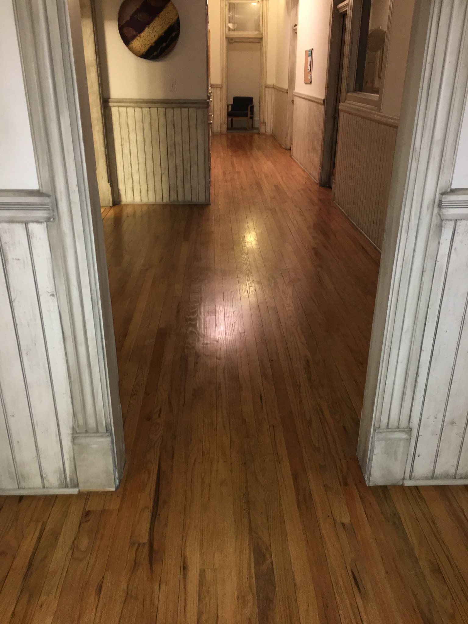 A long hallway with wooden floors and white walls.