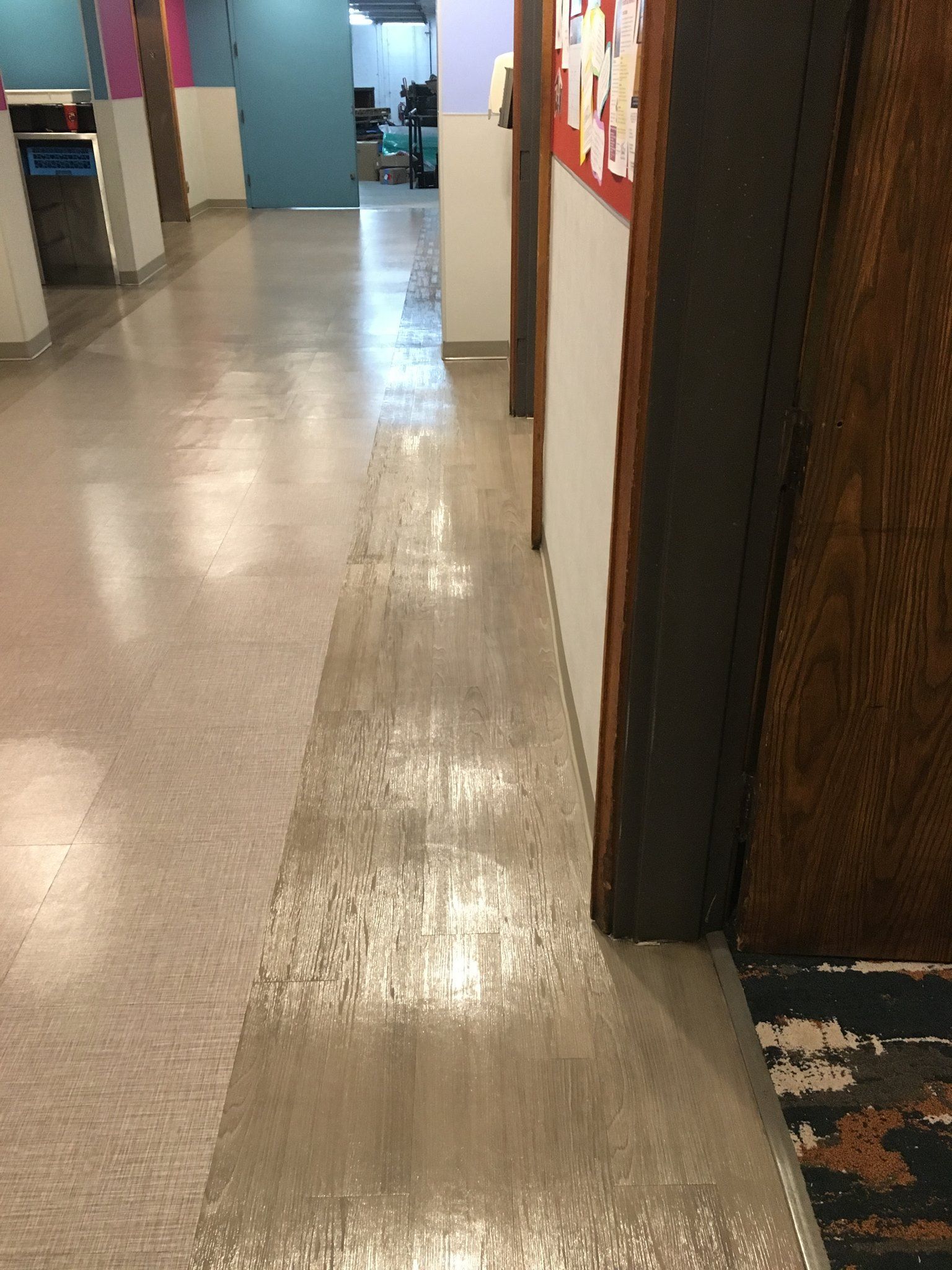A hallway in a building with a shiny floor and a wooden door.