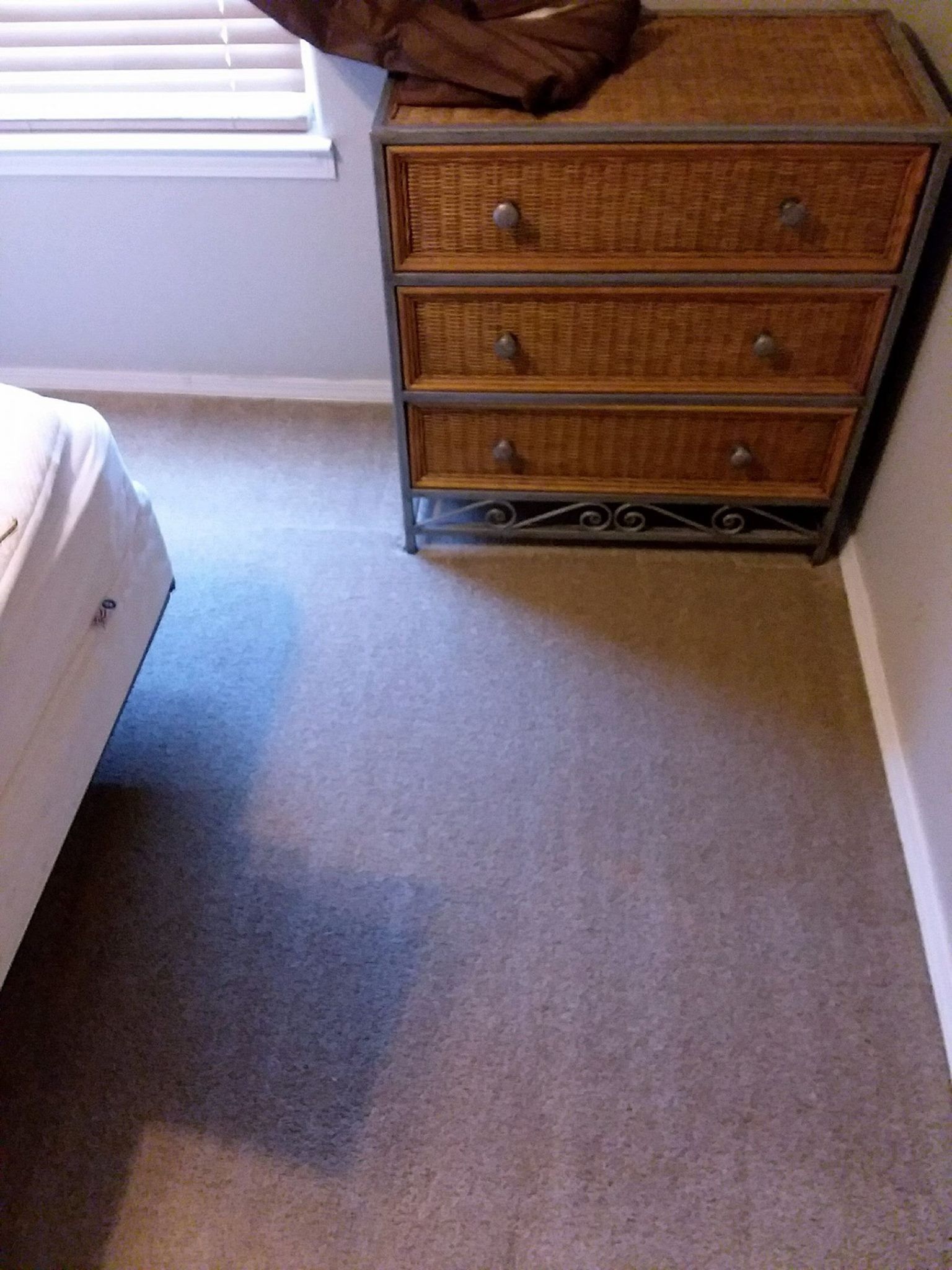 A bedroom with a wicker dresser and a bed.