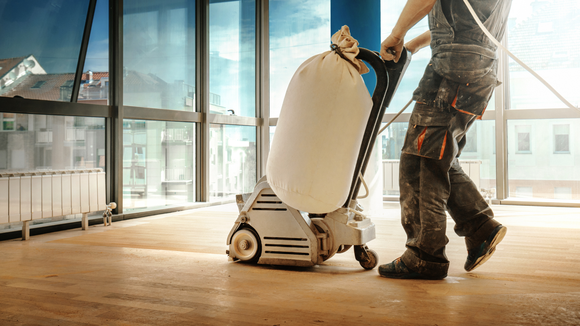 A man is sanding a wooden floor with a machine.