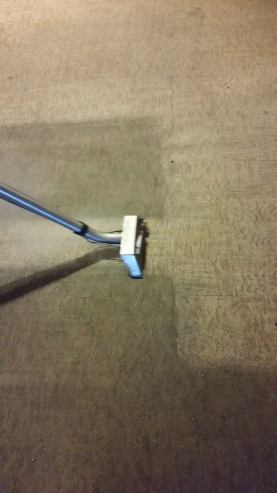 A vacuum cleaner is cleaning a carpet in a room.