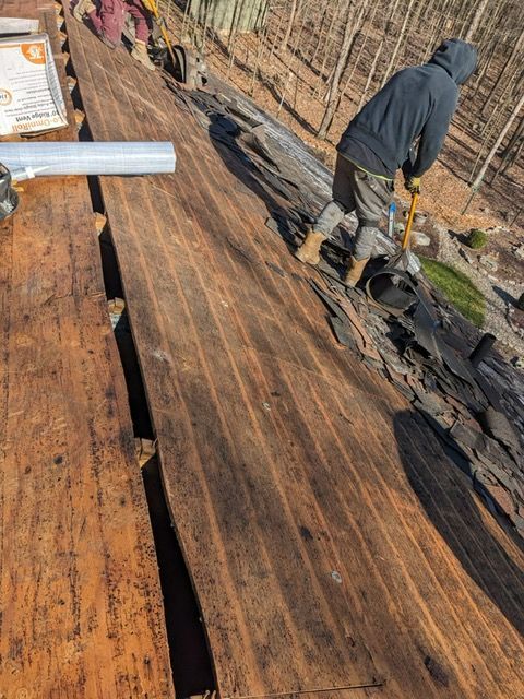 A man is standing on top of a wooden roof.