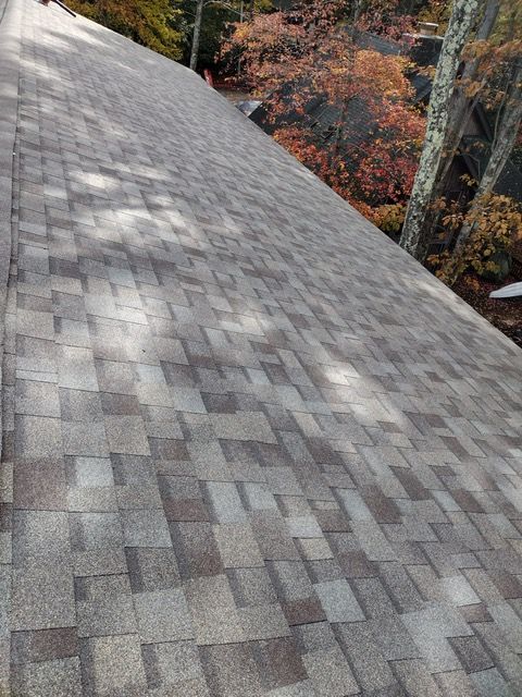 A roof with a lot of shingles on it and trees in the background.