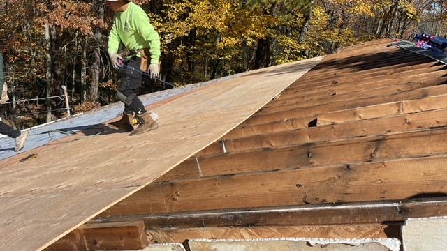 A man is standing on top of a wooden roof.