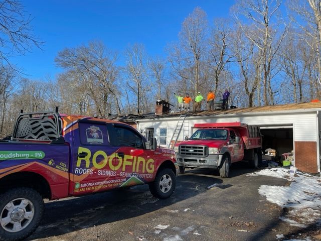 A roofing truck is parked in front of a garage.