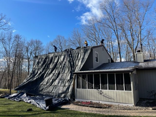 A group of people are working on the roof of a house.