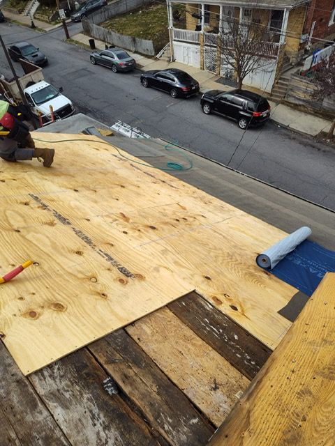 A man is sitting on top of a wooden roof.