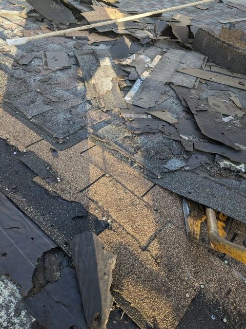 A roof with a lot of shingles laying on the ground