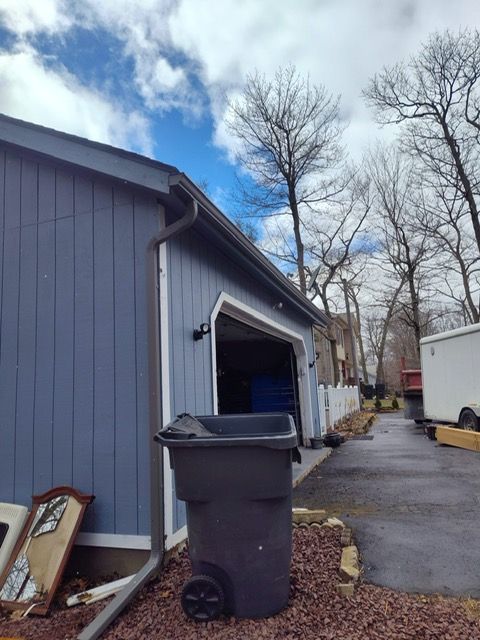 A garbage can is parked in front of a garage