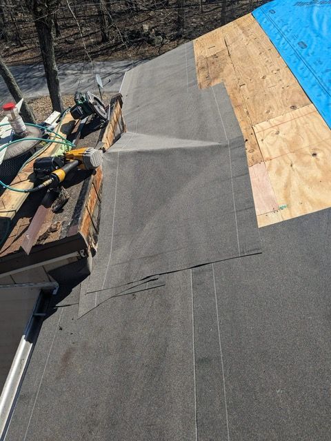 A roof is being repaired with a blue tarp covering it.