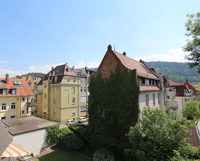 Gebäude mit unterschiedlicher Architektur, darunter eines mit Efeu bewachsen. Klarer blauer Himmel.