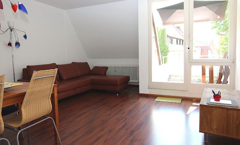 Wohnzimmer mit braunem Ledersofa, Holzböden und großem Fenster.