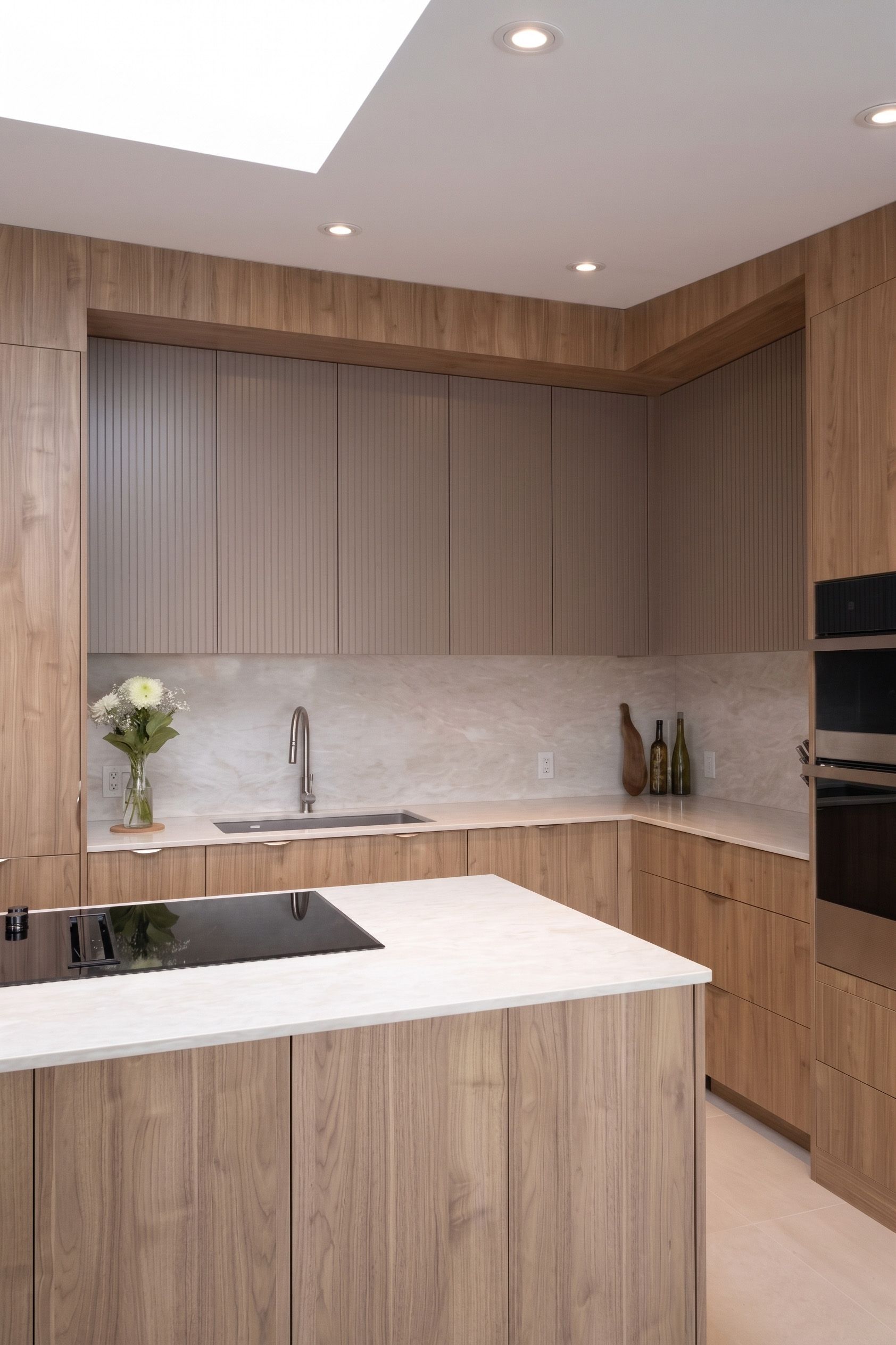 Cuisine moderne avec planchers de bois clair, armoires claires, électroménagers en acier inoxydable et îlot central.