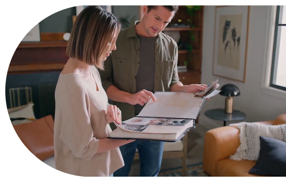A man and a woman are looking at a book in a living room.