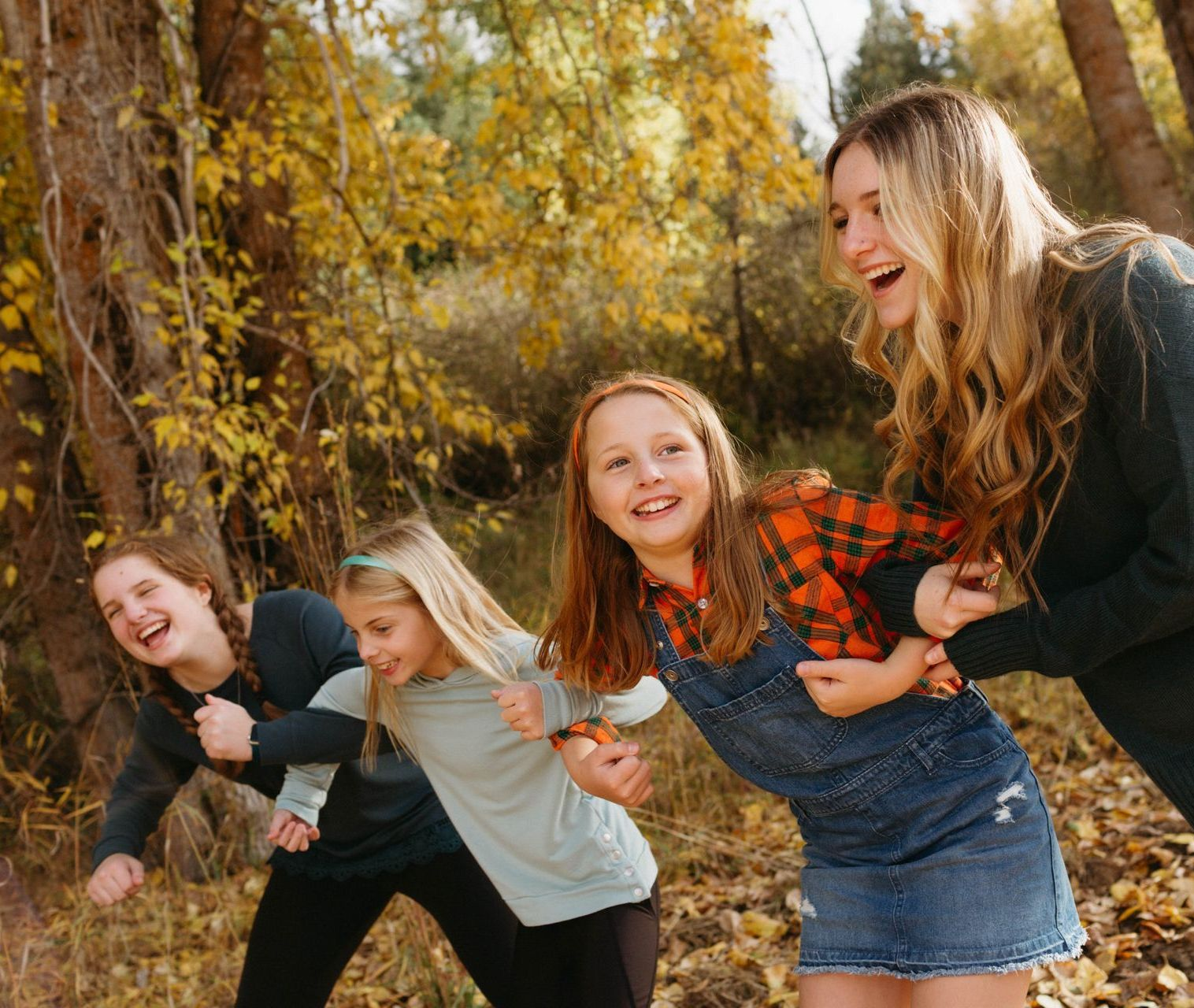 Young women in a park. Their arms are linked and they are smiling.