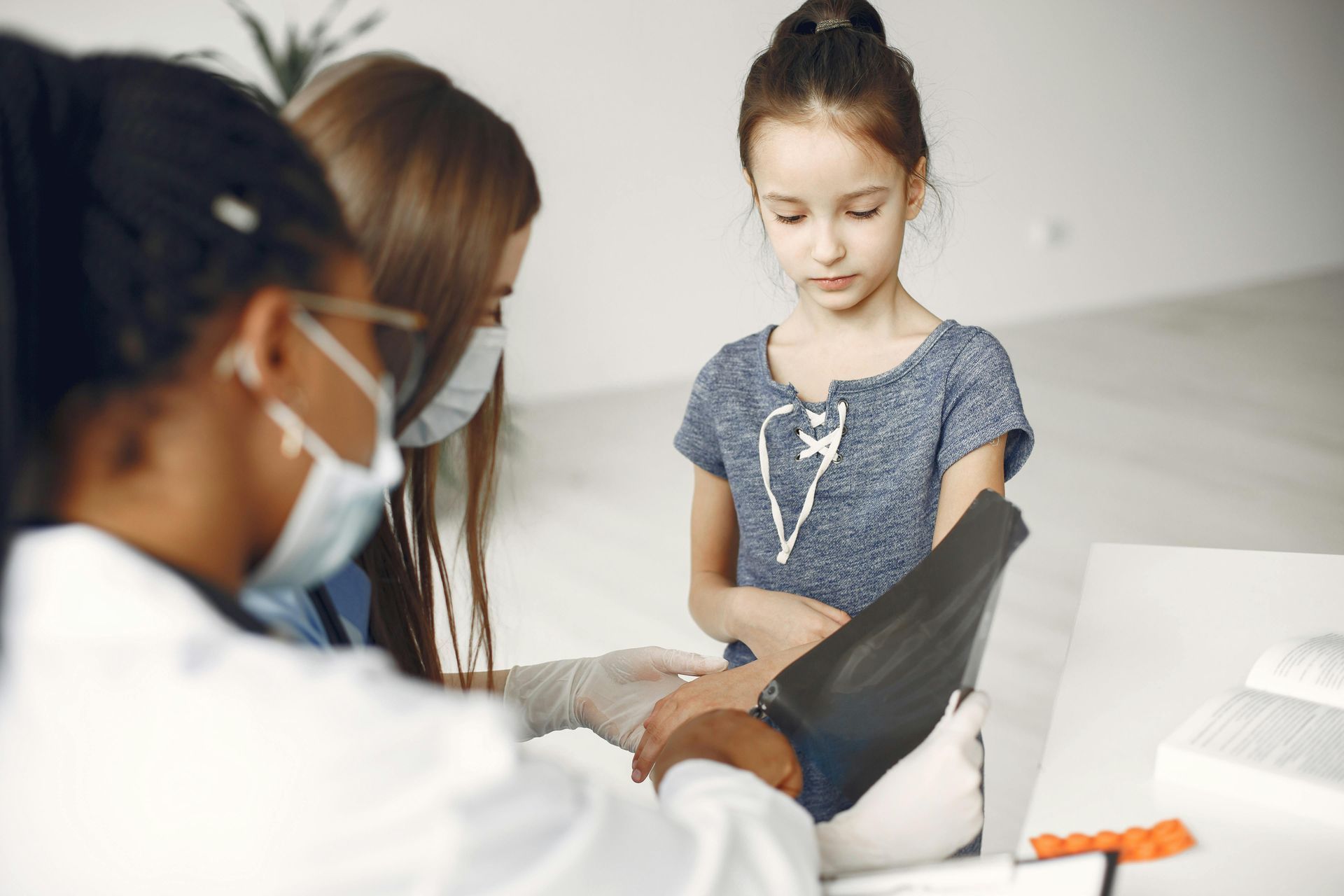 A pediatrician and parent are examining a girl's arm