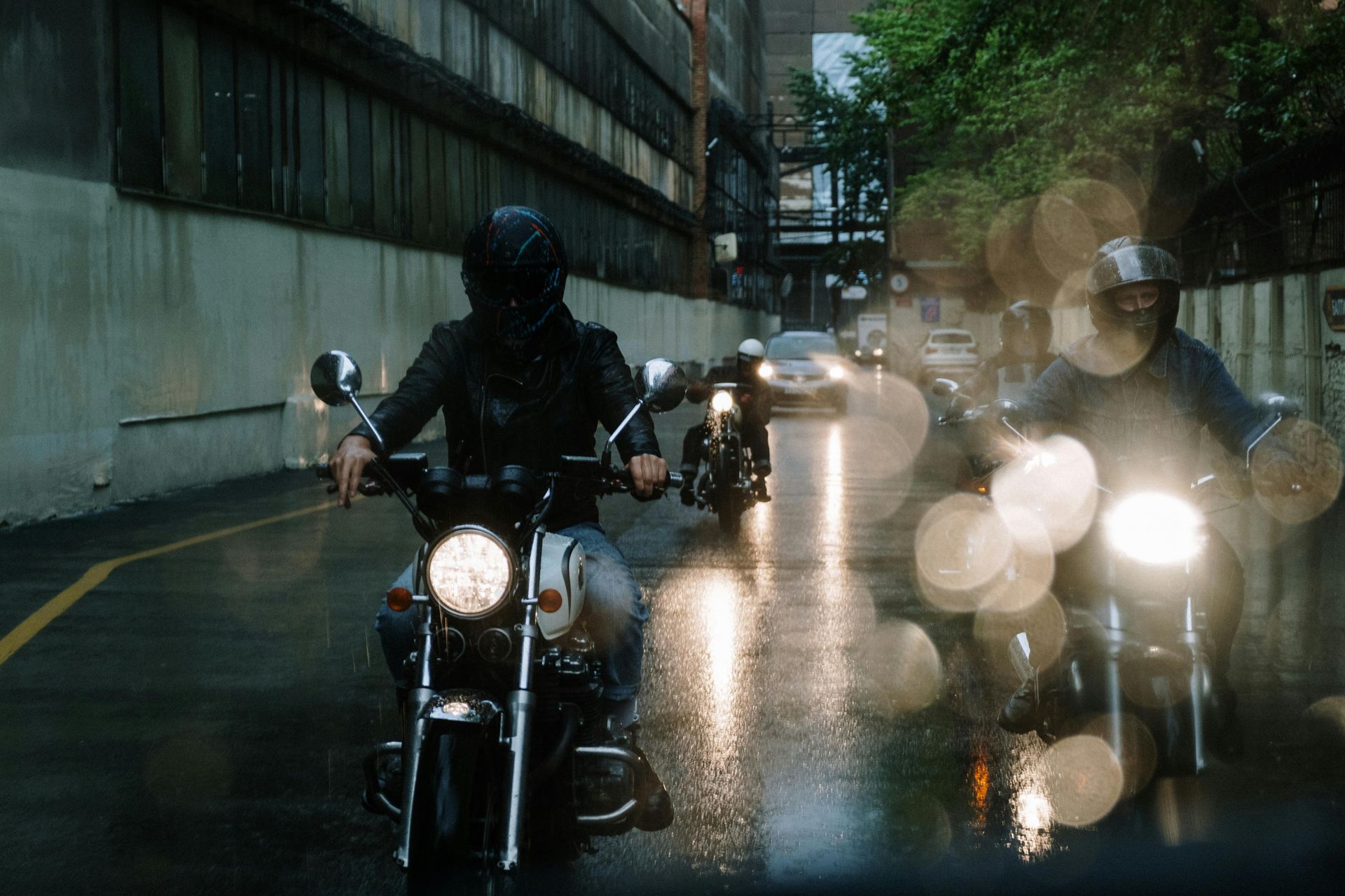 A group of people are riding motorcycles down a wet street.