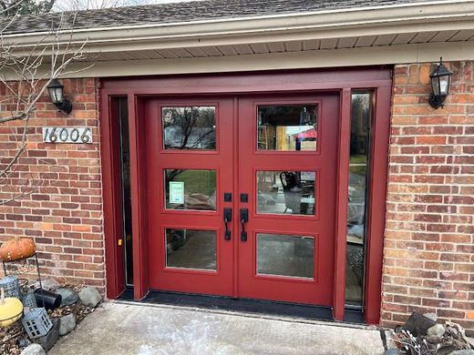 A red double garage door is sitting on top of a brick building.