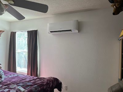 A bedroom with a bed , ceiling fan , and air conditioner.