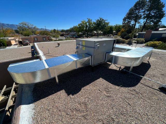 A bunch of pipes are hanging from the ceiling of a basement.