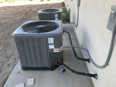 Two air conditioners are sitting on the side of a building.