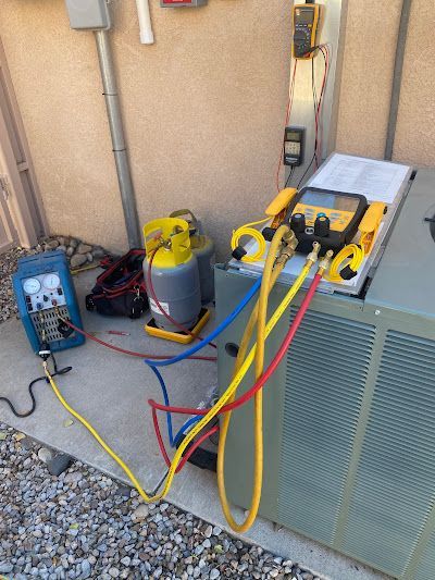 A refrigerator is being serviced by a technician with hose attached to it.