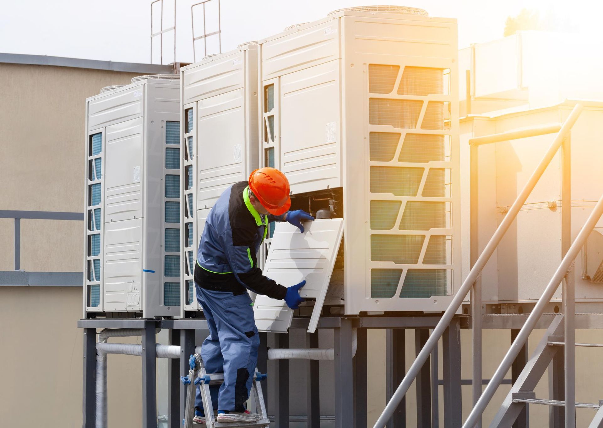 A man is working on an air conditioner on the roof of a building.
