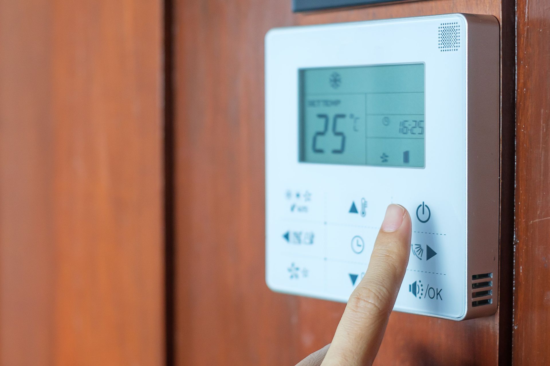 A person is pressing a button on a thermostat.