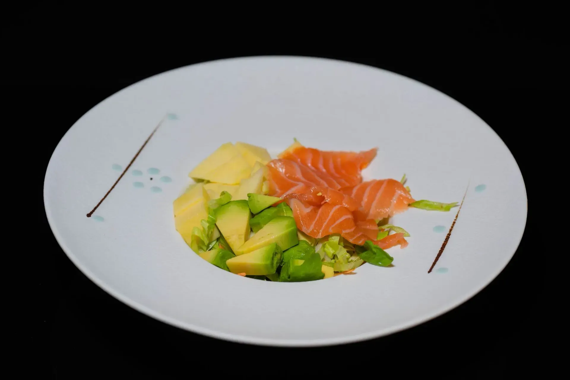 Sushi e sashimi di avocado disposti su un piatto bianco con guarnizioni