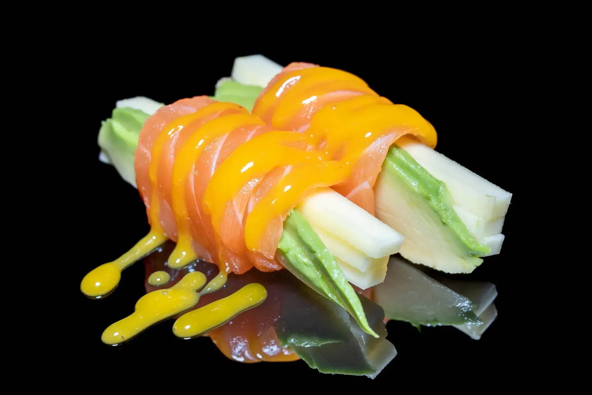 Crudités di verdure condite con salse arancioni e gialle su un piatto nero